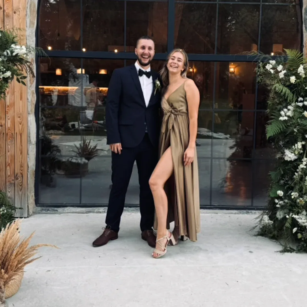 Bohuslav in a suit and bow tie laughing next to a woman in a gold dress